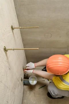 The worker is fixing up a wall of bolts. Stock Photos