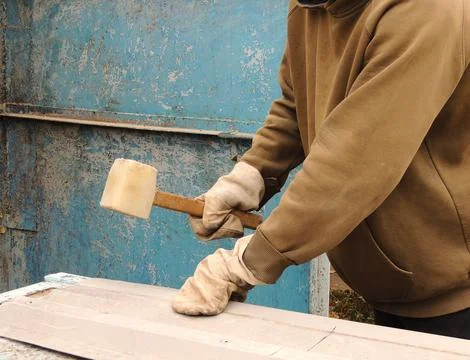 Worker flattens or bends sheet metal with a mallet Stock Photos