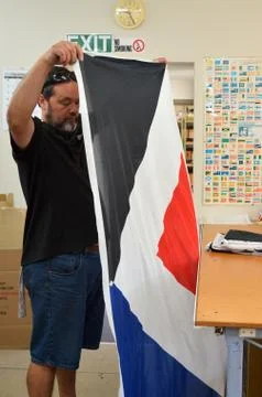 Worker fold the Red Peak flag Stock Photos