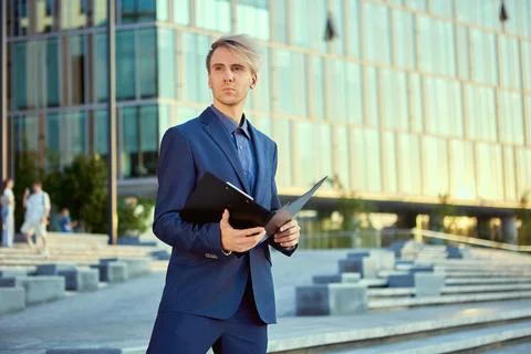Worker with folder for documents stands near office center. Stock Photos