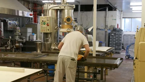 A worker in a food processing facility is folding hot sugar mixture Stock Footage 317841356