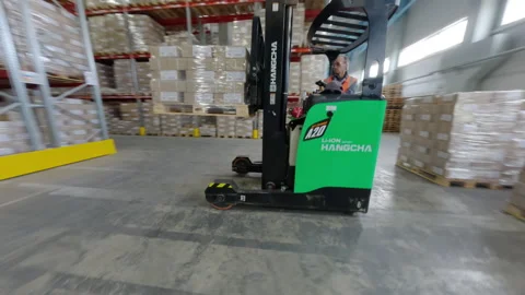 Worker on forklift loader lifts paper packs in storage FPV 動画素材 291337049