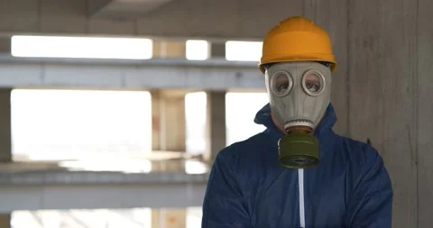 Worker in gas mask, hard hat and protection suit at project site, look at camera Stock Footage 143109579