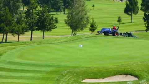 A worker gets into a lawn mower and cuts the grass on a golf course. Stock Footage 262237182