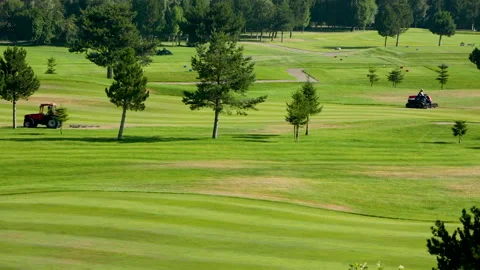A worker gets into a lawn mower and cuts the grass on a golf course. Stock Footage 263422017