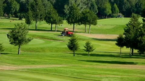 A worker gets into a lawn mower and cuts the grass on a golf course. Stock Footage 263422113