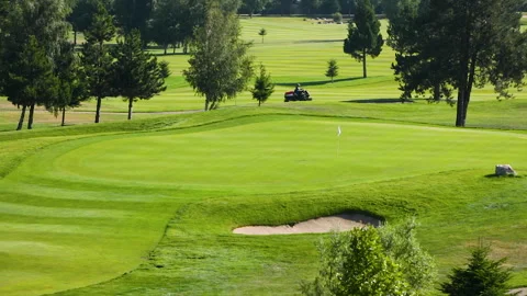 A worker gets into a lawn mower and cuts the grass on a golf course. Stock Footage 263423254