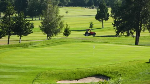 A worker gets into a lawn mower and cuts the grass on a golf course. Stock Footage 263920993