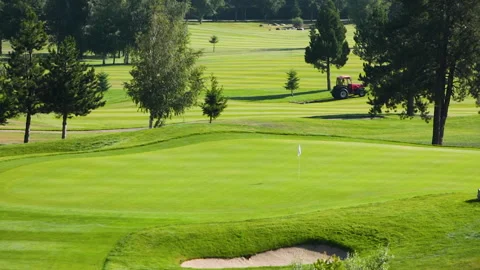 A worker gets into a lawn mower and cuts the grass on a golf course. Stock Footage 263921368