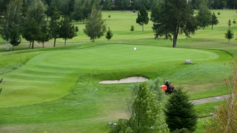 A worker gets into a lawn mower and cuts the grass on a golf course. Stock Footage 263921528