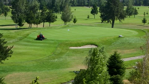 A worker gets into a lawn mower and cuts the grass on a golf course. Stock Footage 264785046