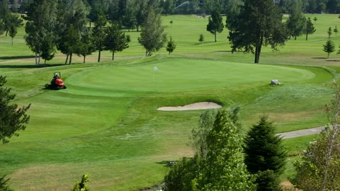A worker gets into a lawn mower and cuts the grass on a golf course. Stock Footage 264785196