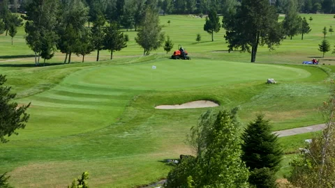 A worker gets into a lawn mower and cuts the grass on a golf course. Stock Footage 264787357