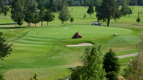 A worker gets into a lawn mower and cuts the grass on a golf course. Stock Footage 264787915