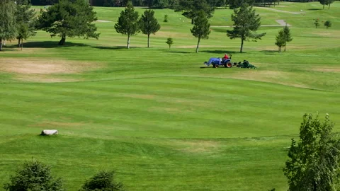 A worker gets into a lawn mower and cuts the grass on a golf course. Stock Footage 265001813