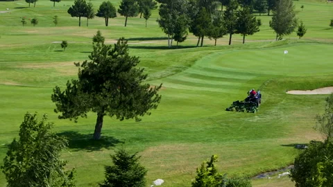 A worker gets into a lawn mower and cuts the grass on a golf course. Stock Footage 265002118