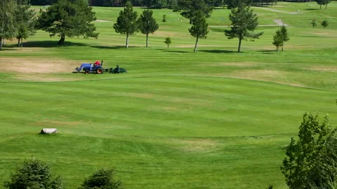 A worker gets into a lawn mower and cuts the grass on a golf course. Stock Footage 265002138