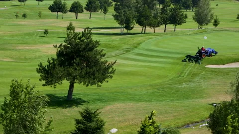 A worker gets into a lawn mower and cuts the grass on a golf course. Stock Footage 265002330