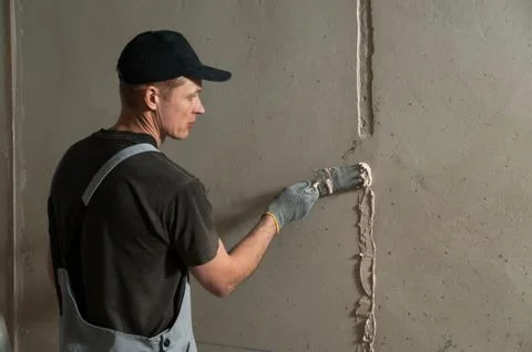 Worker gets plaster on the wall Stock Photos