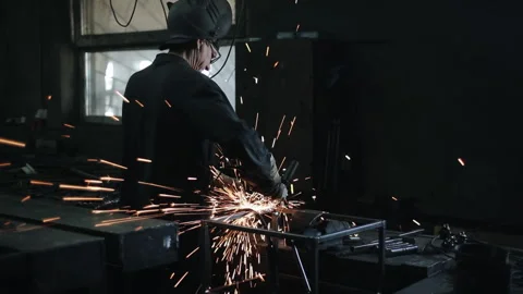 A worker with glasses and protective gloves handles welds with an electric Stock Footage 135747269