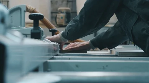 A worker with glasses saws material in production and looks at the result Stock Footage 104497623