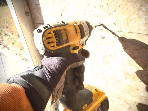 A worker in a glove tightens a screw using a screwdriver Foto stock