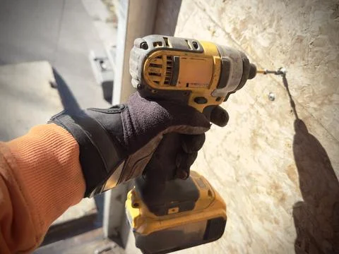 A worker in a glove tightens a screw using a screwdriver Foto stock