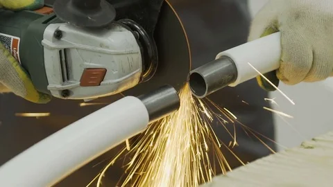 Worker in gloves cutting a metal pipe in two pieces with angle grinder Stock Footage 73642373