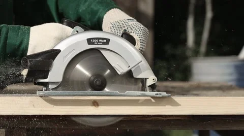 Worker in gloves cutting a wooden plank with hand circular saw Stock Footage