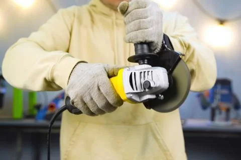 Worker in gloves holds angle grinder turned on Stock Photos