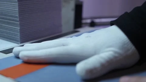 Worker in gloves layers orange material on purple for stitching preparation. Stock Footage 313815364