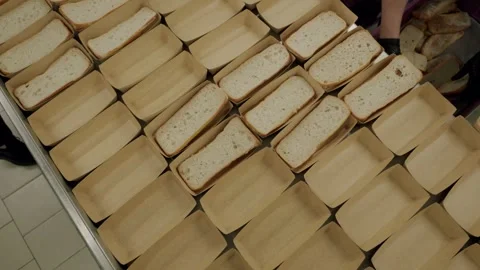 Worker in gloves places sliced bread into paper trays on a table, showcasing a Stock Footage 340172410
