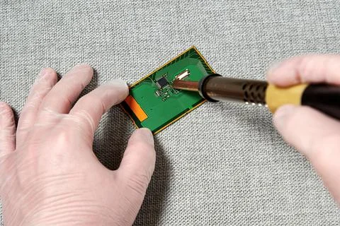 A worker in gloves repairing a pcb with a microchip Stock Photos