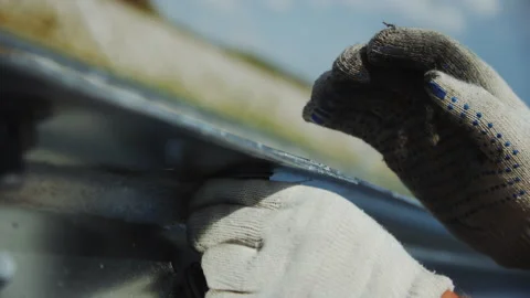 Worker in gloves screws nut on traffic fence on freeway Stock Footage 252918090