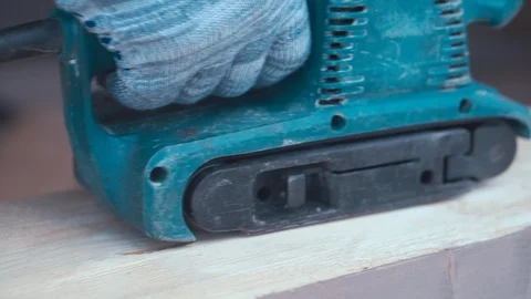 A worker in gloves works with a sanding machine. Wood surface treatment Stock Footage 127585968