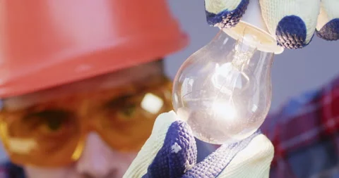 Worker with goggles checks light-bulb to ensure proper function Stock Footage 258503609
