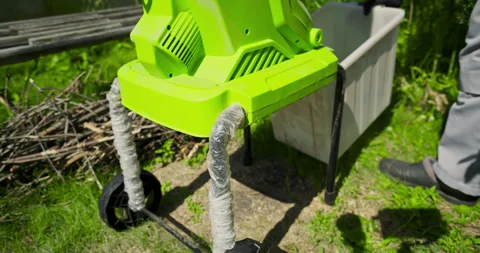 Worker in gray overalls prepares garden wood chipper for operation, installs Stock Footage 313558113