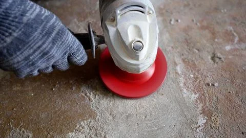 Worker in grey glove using angle grinder with red disc to polish dusty conc.. Stock Photos