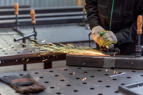 Worker grinding the junction between two sections of a metal square tube Stock Photos