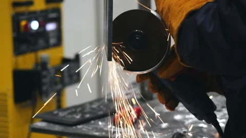 Worker grinding metal with angle grinder producing sparks in factory. 스톡 동영상 347788909