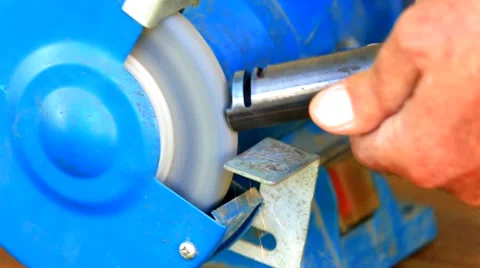 Worker grinding metal component on bench grinder Stock Footage 58815586