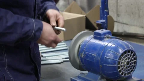 A worker is grinding a metal part on a grinder Stock Footage 340558937