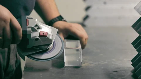 Worker grinding metal piece in a workshop. A close-up of a worker using an Stock Footage 284434668