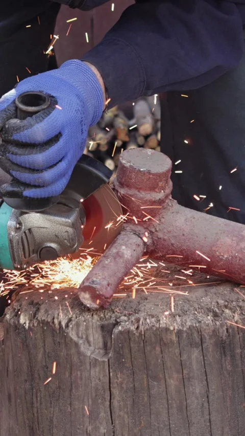 Worker grinding metal pipe with power tool on wooden stump, generating brig.. Stock Footage 339084441