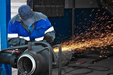 Worker Grinding Metal Pipe in Workshop With Sparks Flying Stock Photos