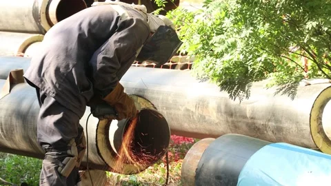 A worker grinds the end of a metal pipe with a grinder to repair the heating Stock Footage 184346107