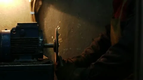 A worker grinds smooth a detail on a sharpening machine-tool Stockbeeldmateriaal 11339438