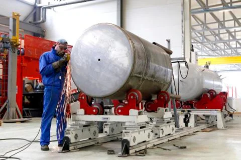 The worker grinds the welds of the barrel Stock Photos