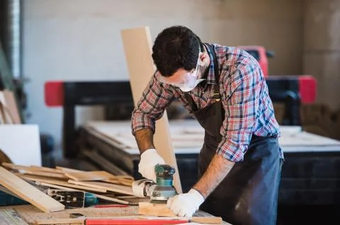 Worker grinds the wood of angular grinding machine Stock Photos