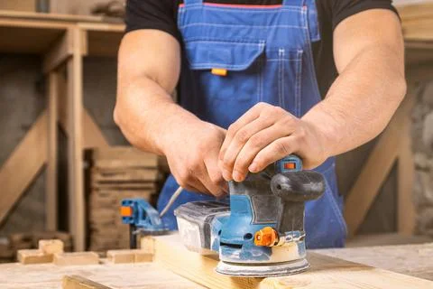 Worker grinds the wood of angular grinding machine Stock Photos